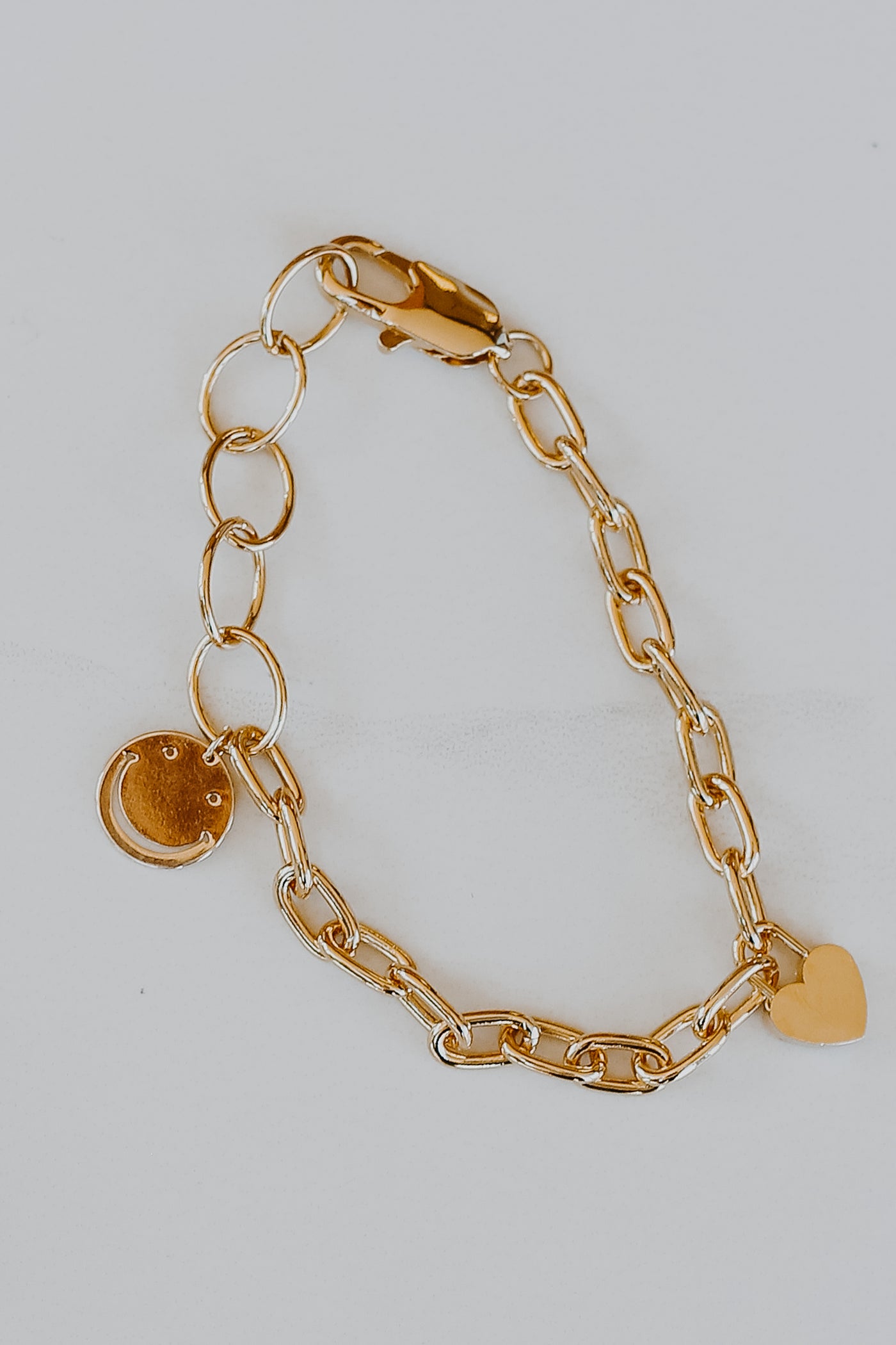 flat lay of a Gold Smiley Face + Heart Charm Bracelet