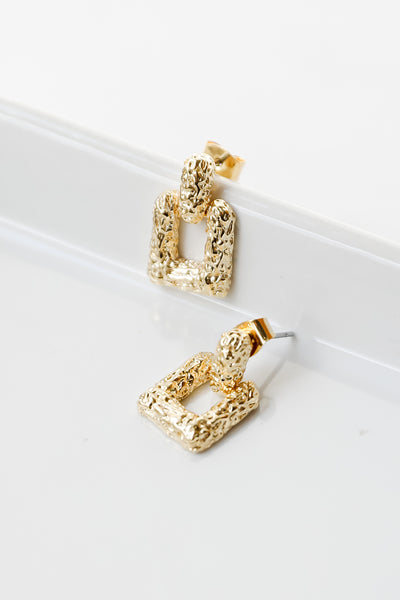 flat lay of gold square earrings