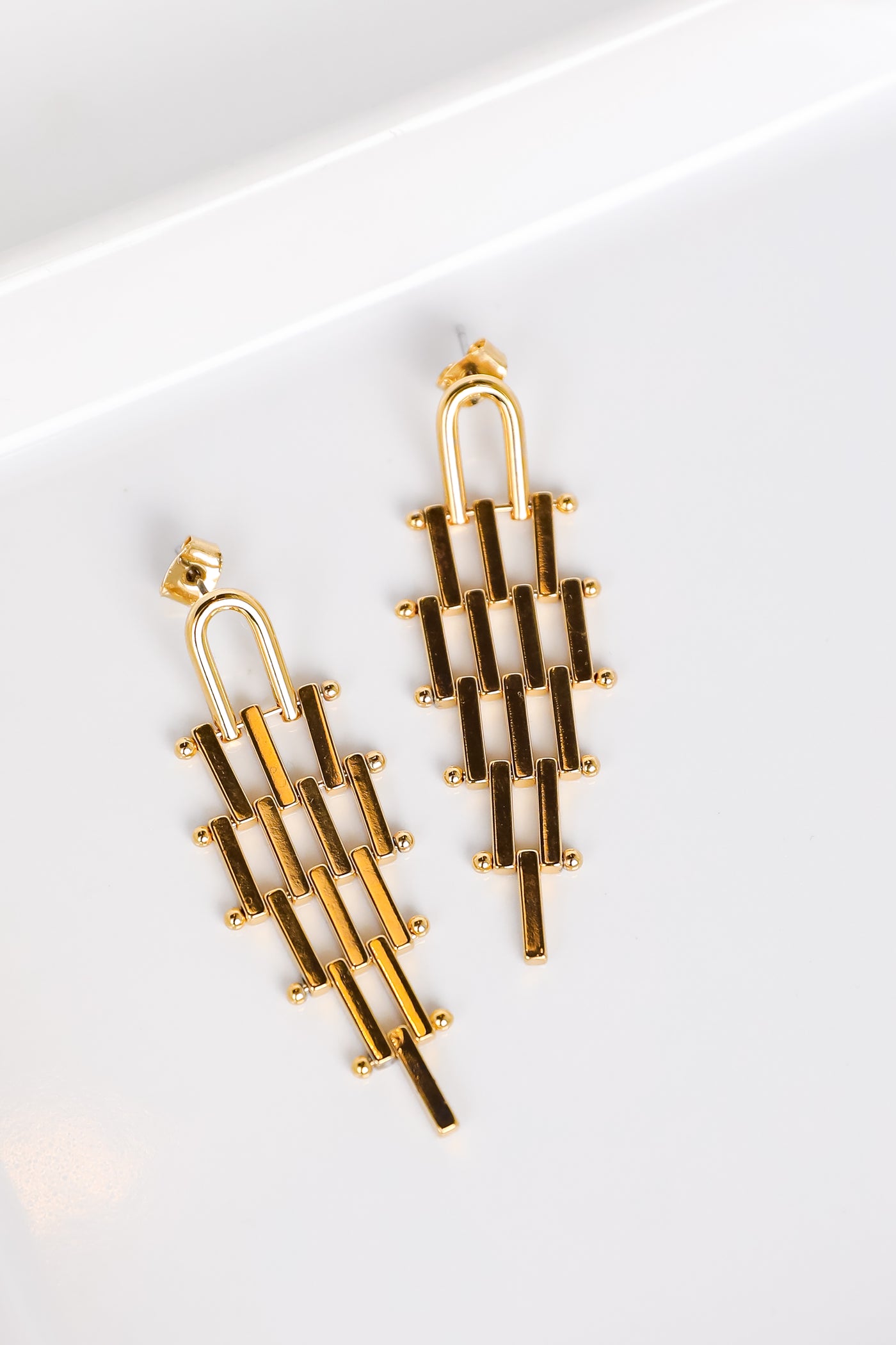 gold tiered earrings flat lay