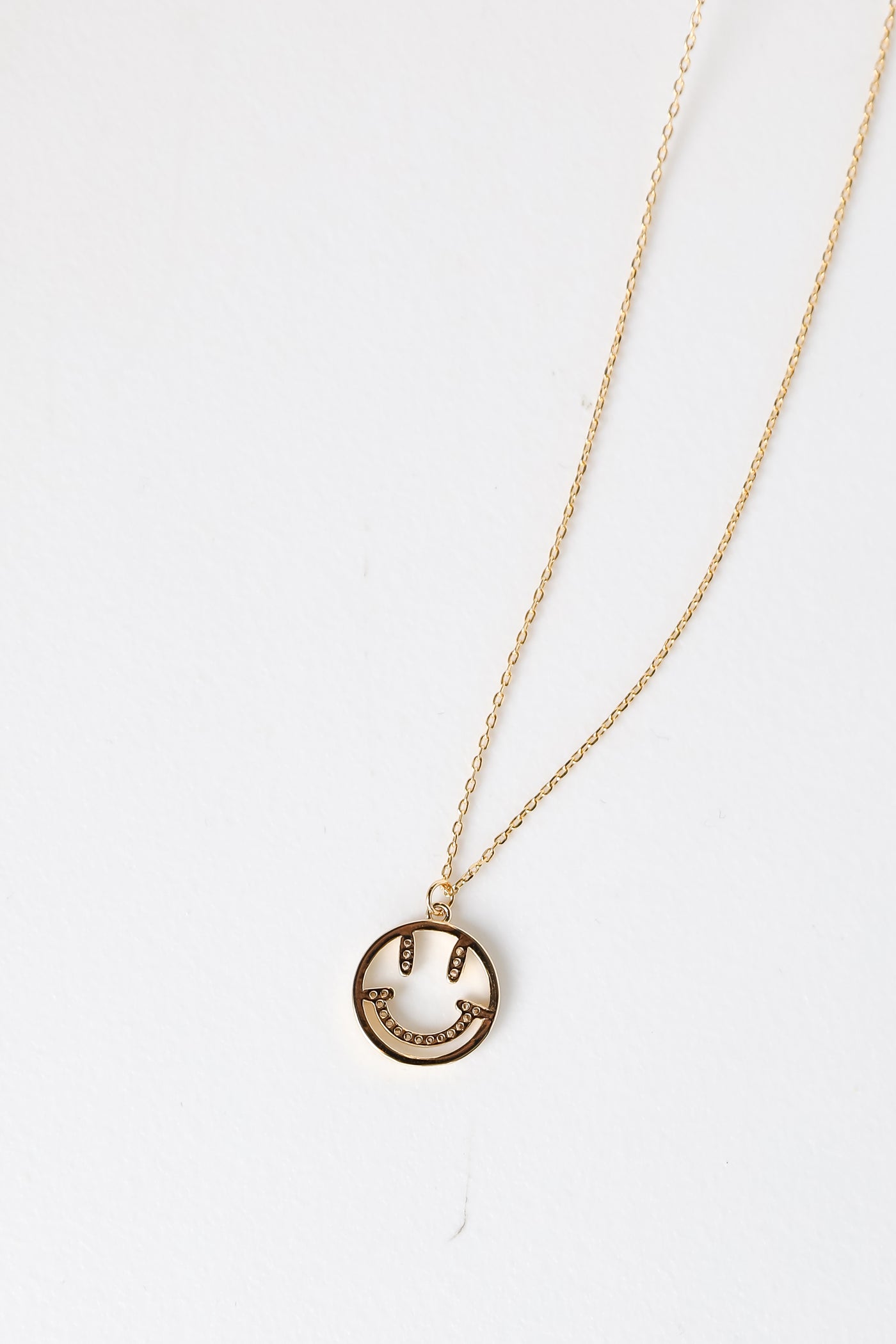 Gold Rhinestone Smiley Face Charm Necklace flat lay
